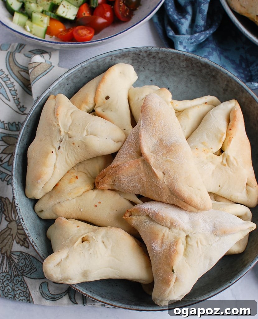 Golden, triangle-shaped Spinach Fatayer pastries artfully arranged in a rustic bowl, ready for serving.