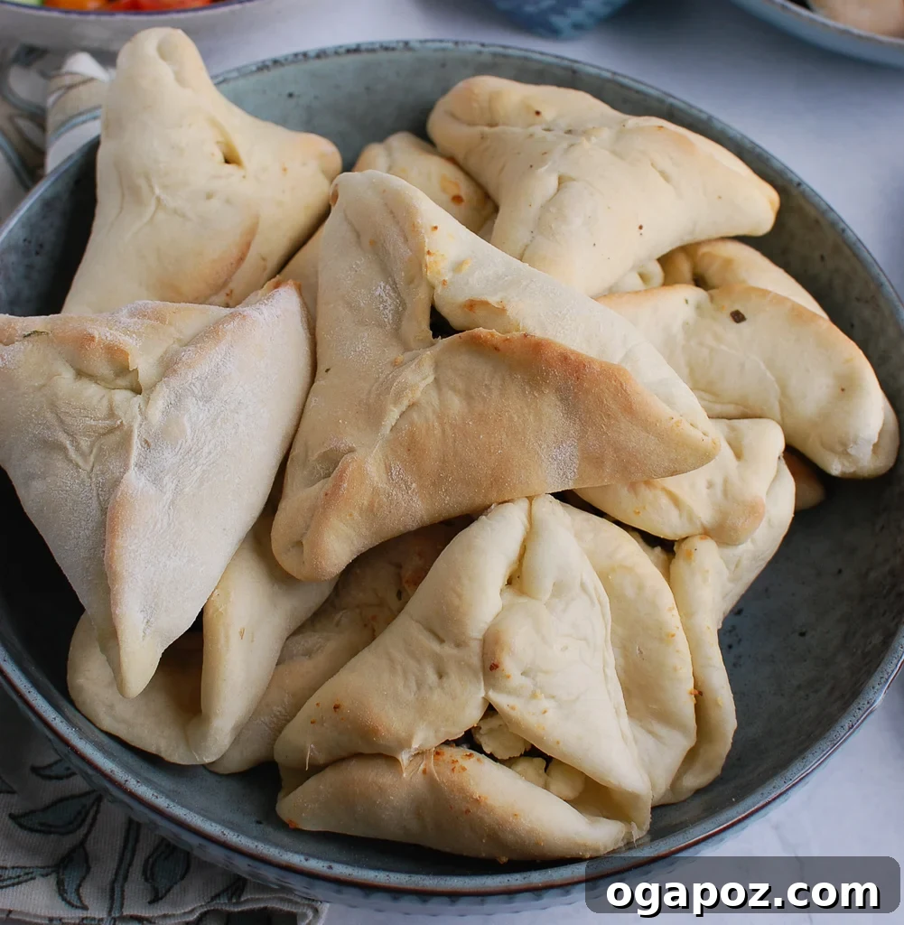 Freshly baked fatayer triangles filled with a rich spinach and cheese mixture, perfectly arranged on a baking sheet.