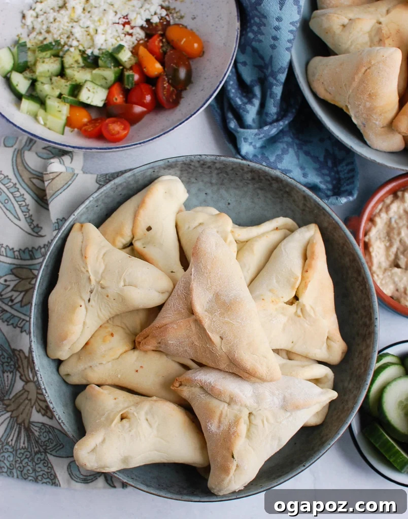 A large, ornate bowl overflowing with an abundance of freshly baked Lebanese Spinach Fatayer, ready to be enjoyed.