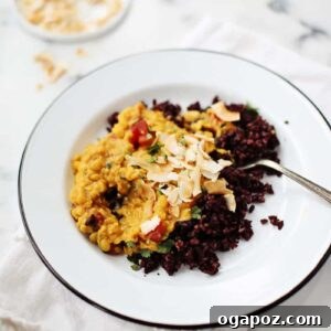A vibrant bowl of Coconut Curried Lentils, garnished with fresh cilantro and toasted coconut flakes, ready to be served.