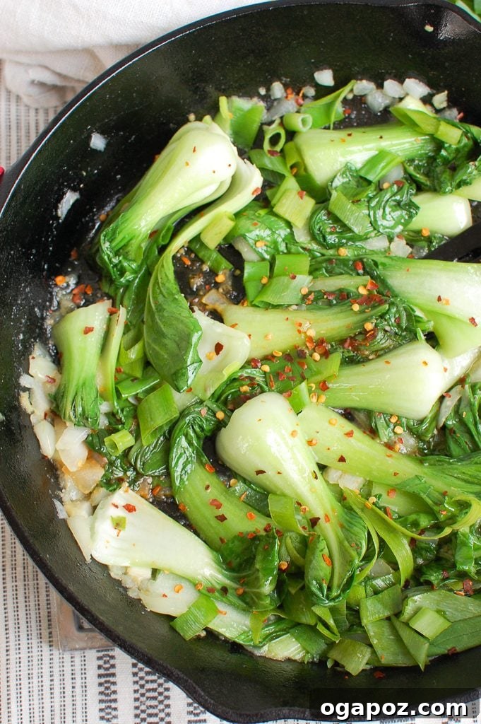 No-Fuss Garlic Bok Choy 5 Cooking Easy Bok Choy Recipe in a black cast iron skillet on the stove, mid-sauté