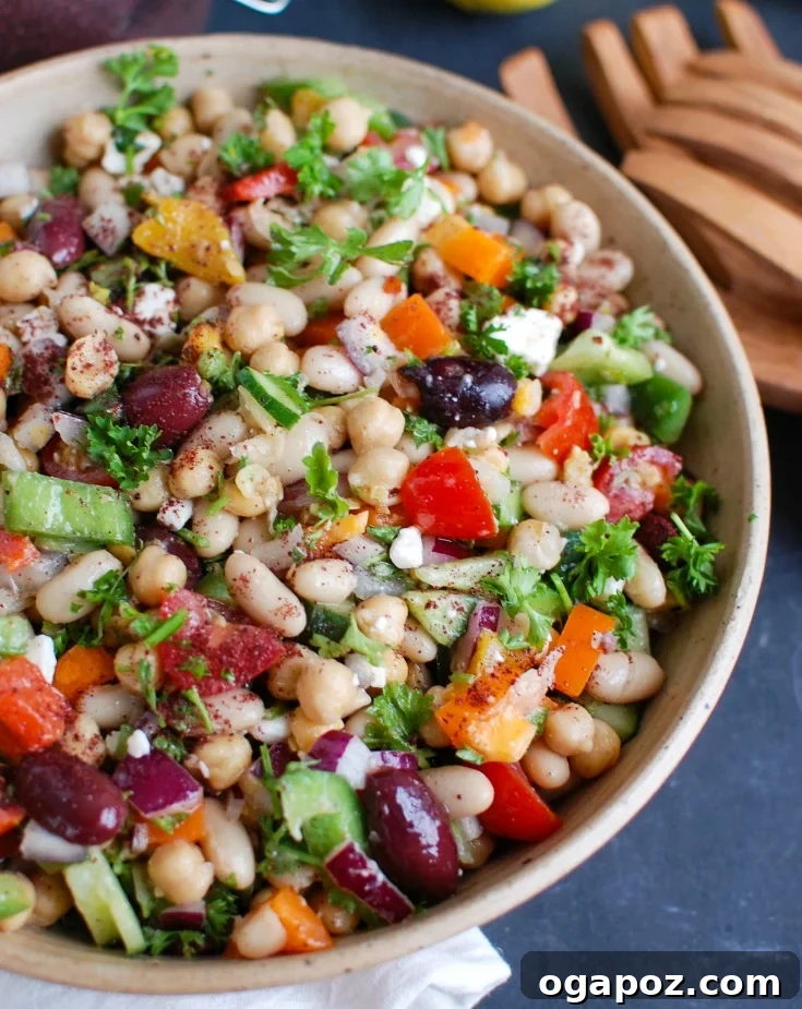 A vibrant and colorful Mediterranean Bean Salad, packed with chickpeas, kidney beans, chopped vegetables, and fresh parsley, all tossed in a light dressing.