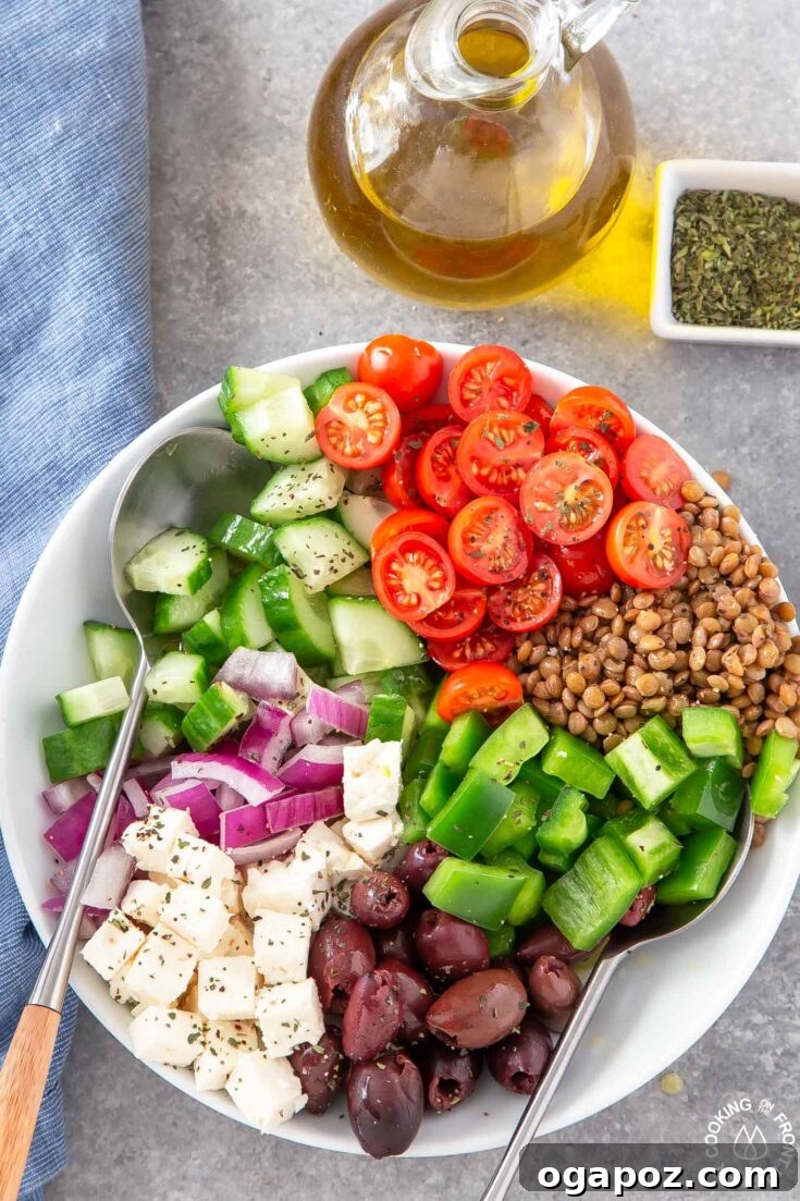 A nutritious Lentil Greek Salad, featuring earthy lentils mixed with fresh tomatoes, cucumbers, red onion, olives, and crumbled feta cheese.
