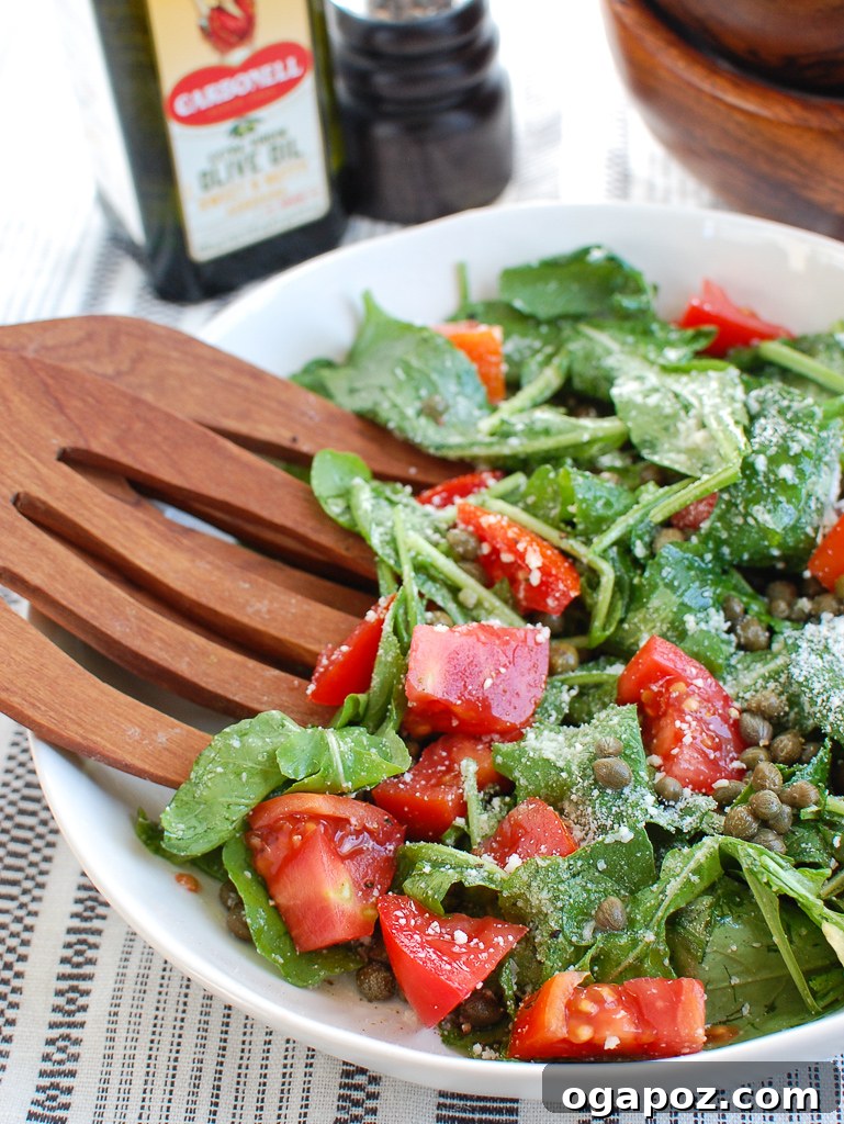 Rocket and Caper Salad 5 A freshly prepared Arugula Salad with Capers, shown with elegant wooden serving spoons, ready to be enjoyed. Simple, healthy, and full of flavor. #arugulasalad #caperrecipe #healthyfood