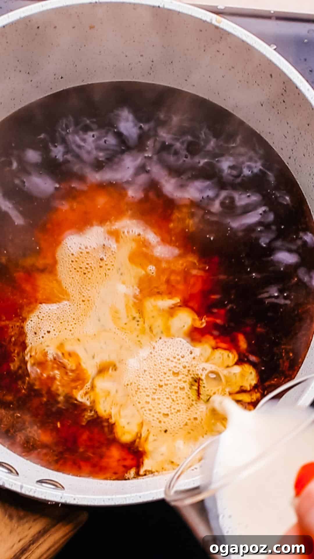 Authentic Karak Chai Made Simple 7 Evaporated milk being poured into the simmering chai in a saucepan, creating a creamy infusion.