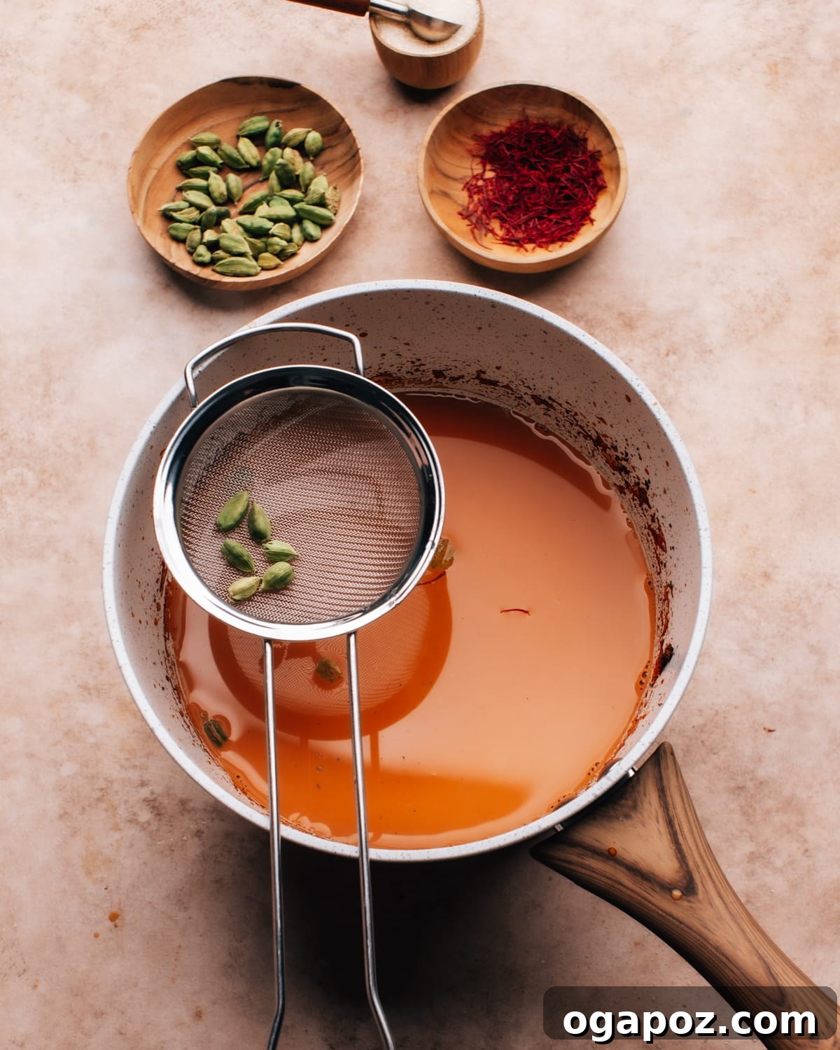 Authentic Karak Chai Made Simple 8 Straining freshly brewed Karak Chai through a small sieve into a saucepan, ensuring a smooth, sediment-free drink.