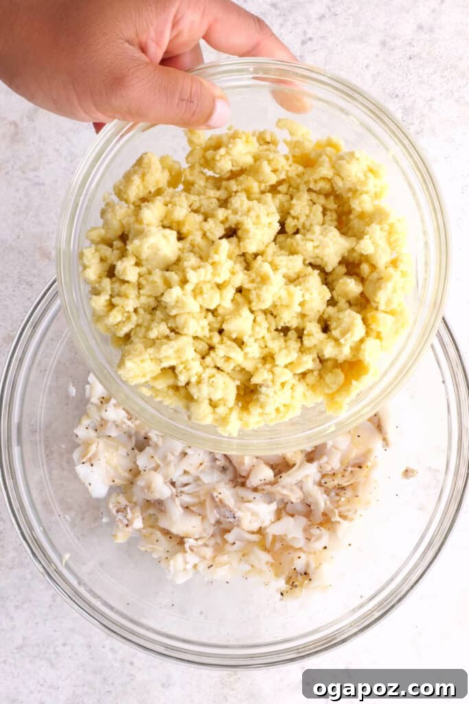 Golden Crispy Cod and Potato Patties 4 Mashed potatoes being added to flaked cod and spices in a mixing bowl.