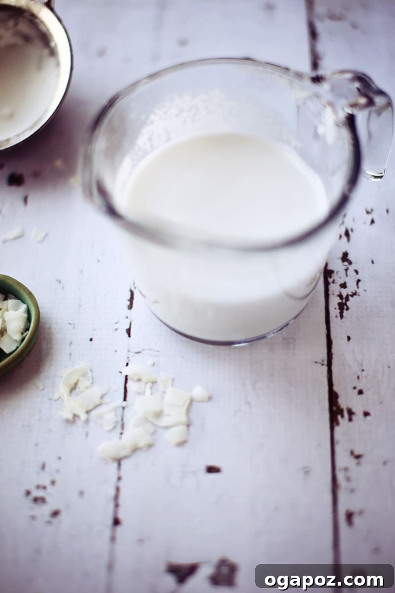 Whip Up Your Own Coconut Milk 5 A clear glass measuring cup holding freshly prepared homemade coconut milk.