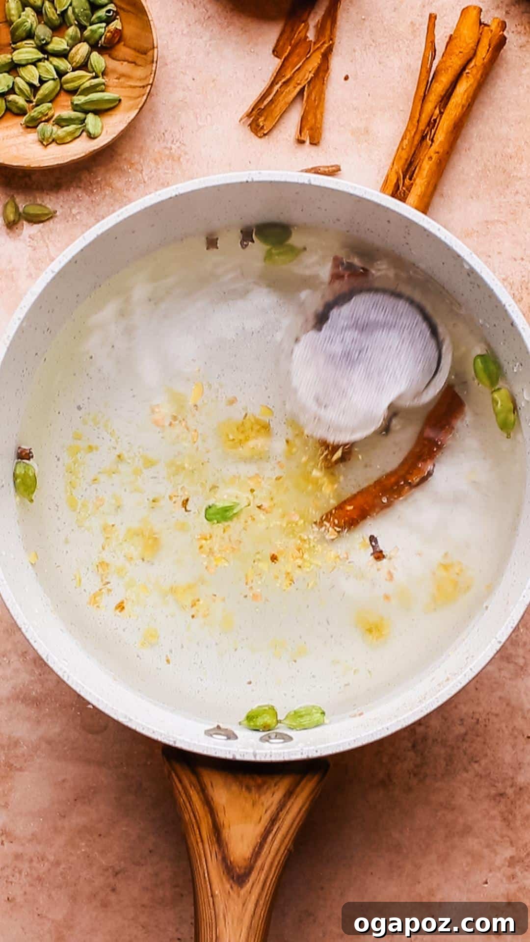 Authentic Chai Concentrate for the Best Homemade Lattes 6 A hand dropping whole cloves and star anise into a pot of simmering water, alongside other spices like cinnamon sticks and ginger, for the chai concentrate.
