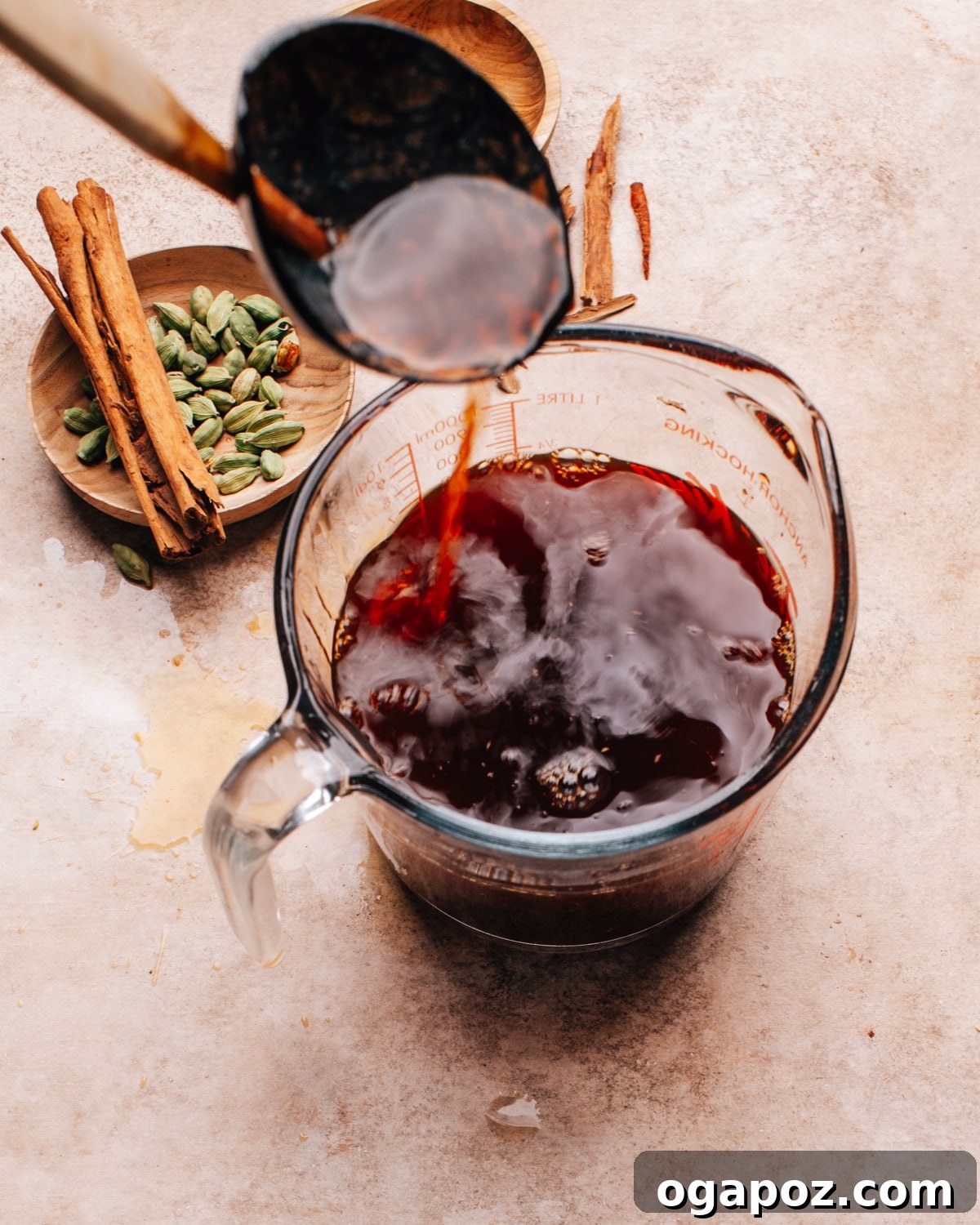 Authentic Chai Concentrate for the Best Homemade Lattes 8 Chai concentrate being strained into a clear glass measuring cup, highlighting its rich, dark color and smooth texture.