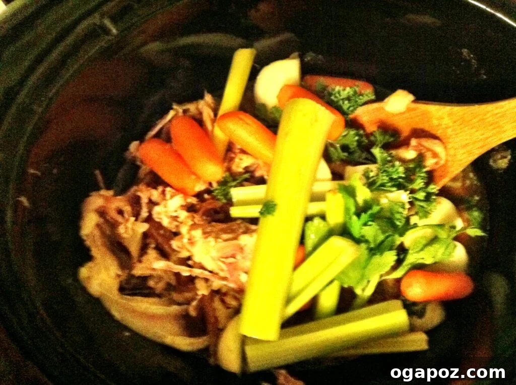 Slow cooker filled with chicken bones, vegetables, and water, ready for making stock.