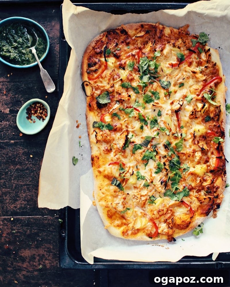 Incredible Indian Dinners Surprisingly Simple to Make 21 Butter chicken pizza (Indian pizza) on a table with small bowls of cilantro and red pepper flakes, a fusion dinner.