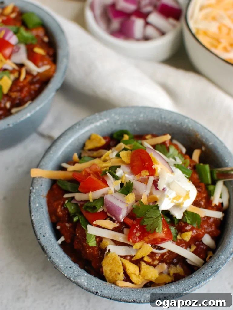 A generous serving of Classic Beef Chili in a bowl, topped with shredded cheddar cheese, ready to be enjoyed.