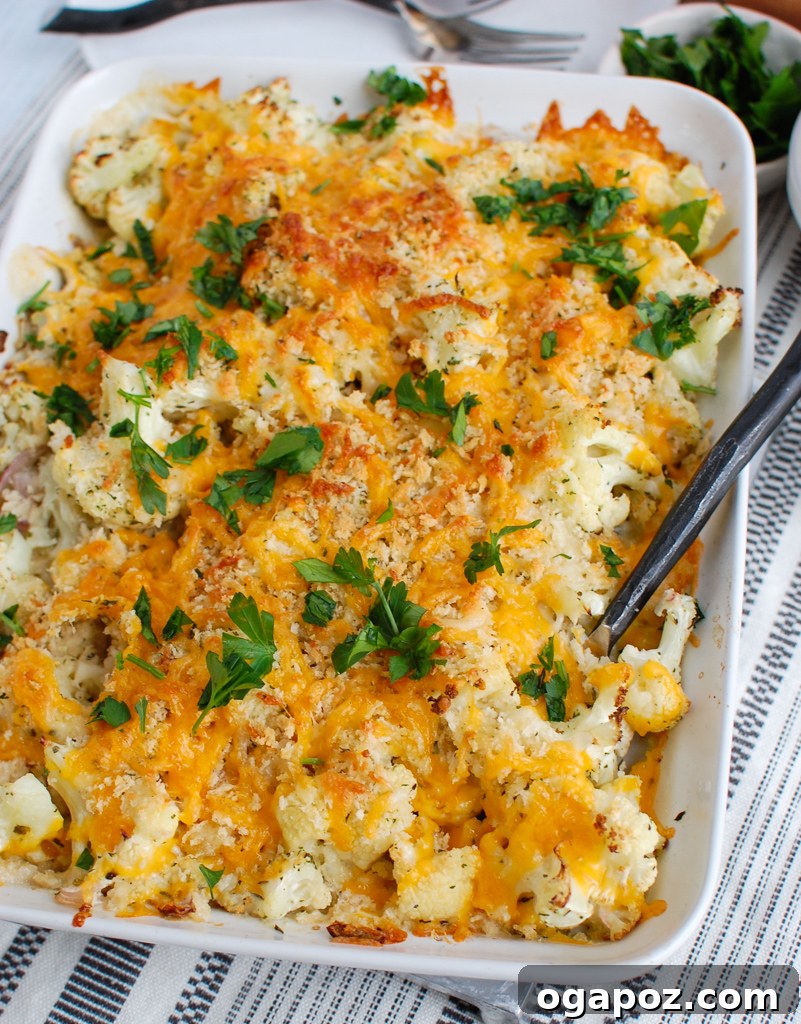 Baked Cheesy Cauliflower 5 A serving of Cauliflower Gratin being scooped from a white baking dish, showcasing its cheesy, golden-brown crust.
