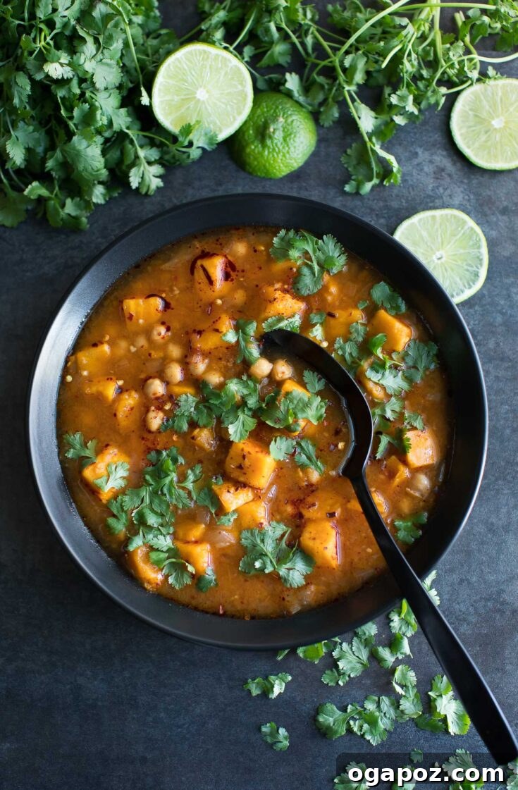 A bowl of vibrant Spicy Moroccan Sweet Potato Soup, a hearty vegan soup with chickpeas, a medley of vegetables, and a flavorful harissa-spiked broth.