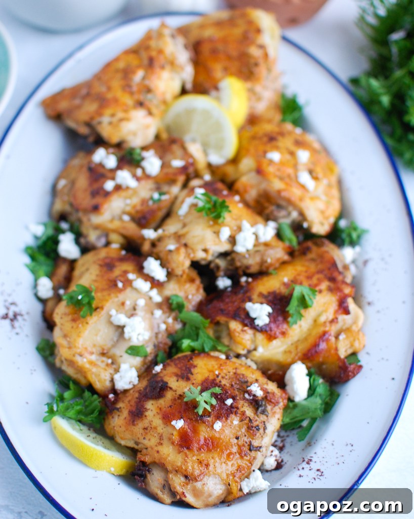 Mediterranean Chicken on a large serving platter with fresh herbs and lemon wedges.
