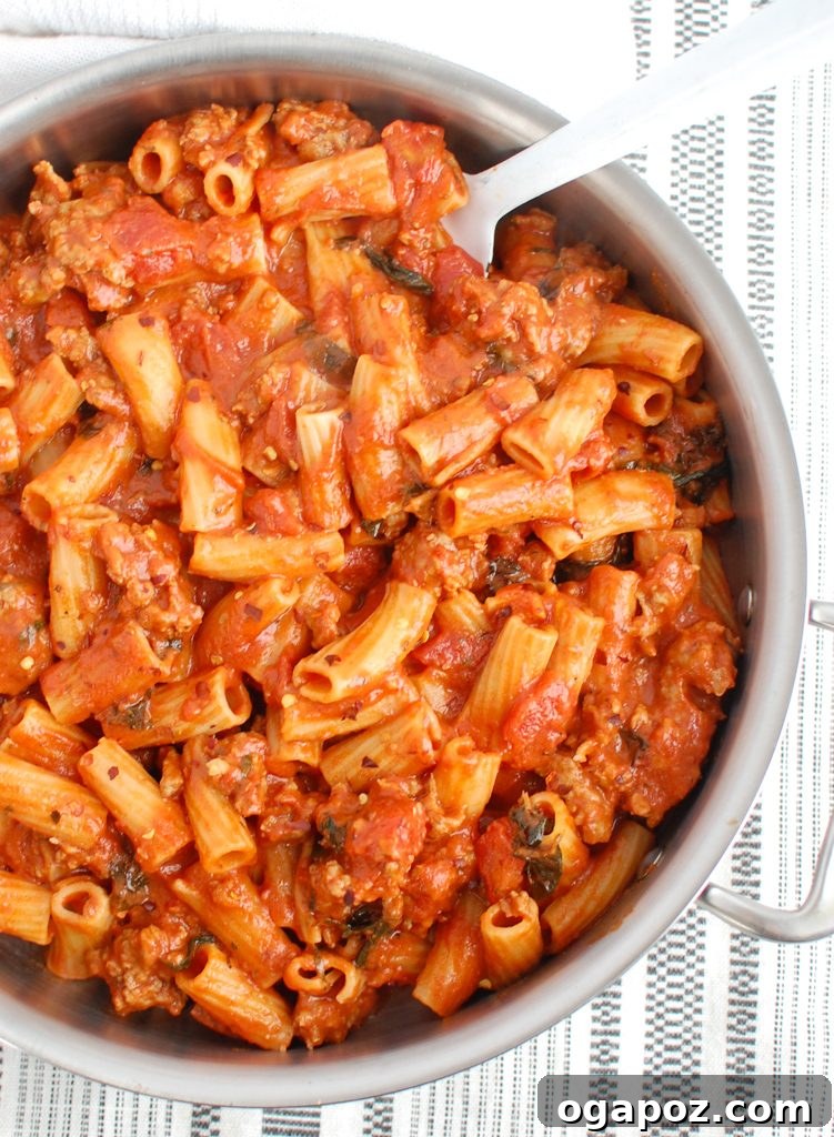 Robust Italian Sausage Pasta 5 A close-up of a serving of Italian Sausage Pasta in a white bowl, with a vintage silver spoon, highlighting the rich texture and vibrant colors.