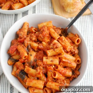 A top-down view of the finished Italian Sausage Pasta dish, garnished with fresh herbs.