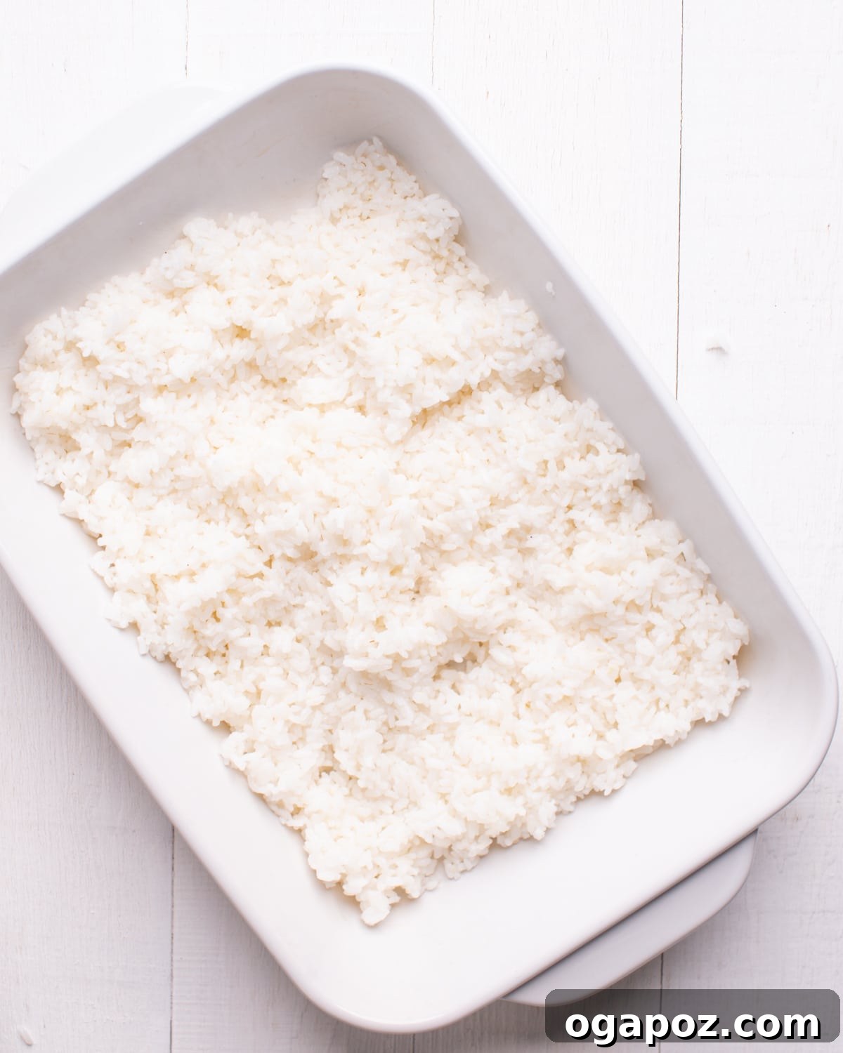 The Ultimate TikTok Sushi Bake 5 Cooked sushi rice being spread evenly in a baking dish.