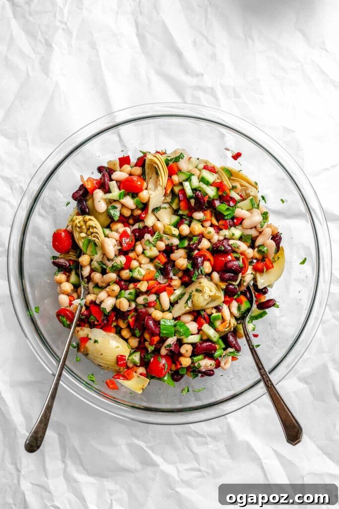 Vibrant Mediterranean Three Bean Salad 7 A large bowl of Mediterranean Three Bean Salad with two serving spoons, ready for tossing.