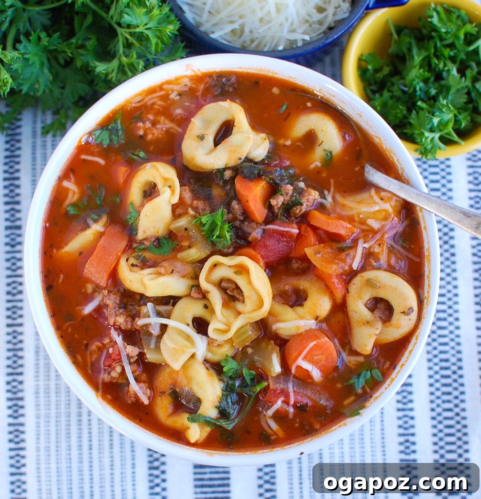 Italian Sausage and Tortellini Soup 4 Spoon lifting a generous portion of Tortellini Sausage Soup from a white bowl, showing all the hearty ingredients