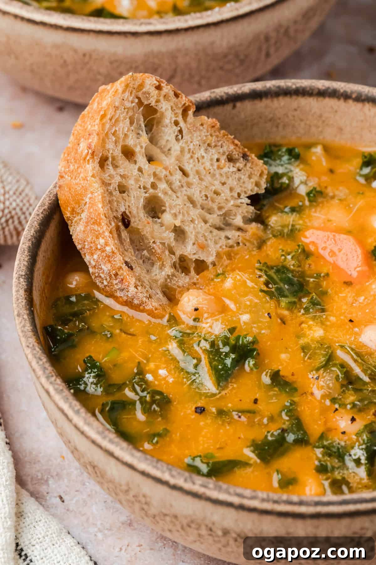 A close-up shot of creamy Tuscan white bean soup, made with perfectly cooked cannellini beans, highlighting its smooth and inviting texture in a rustic bowl.