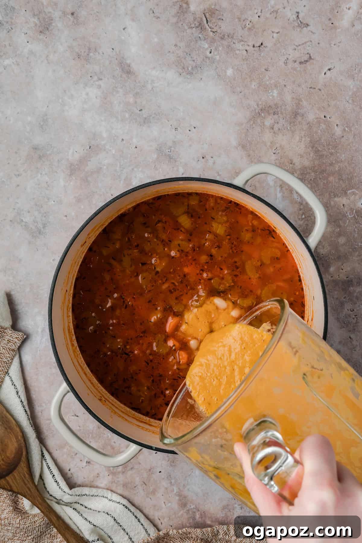 Tuscan soup with white beans, vegetable broth, and a bay leaf simmering in a Dutch oven, creating a rich and flavorful base before partial blending for creaminess.