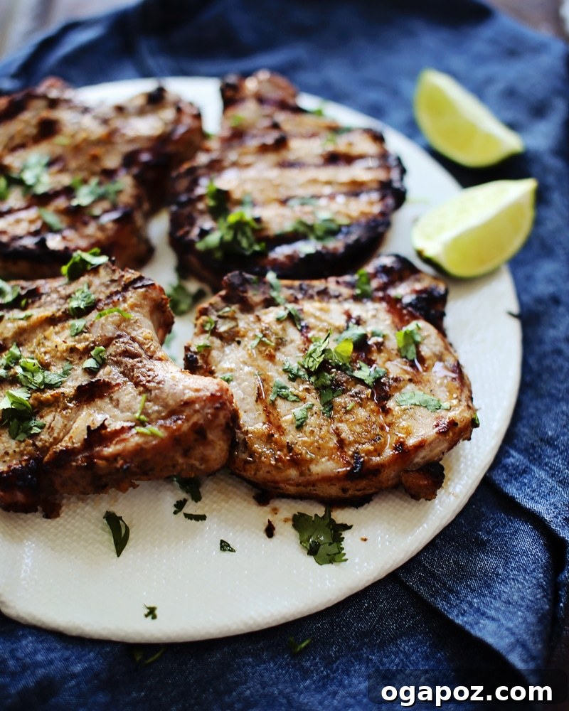 Island Jerk Pork Steaks 3 Close-up of a beautifully grilled pork chop on a plate, garnished with fresh herbs and lime.