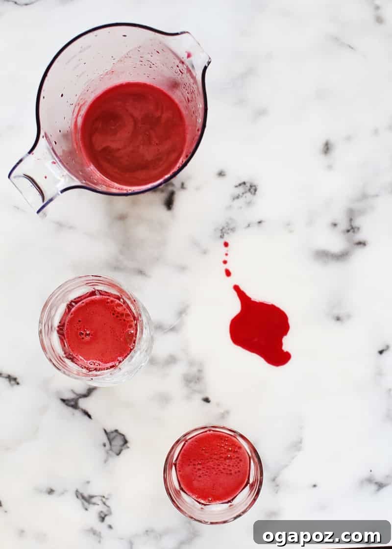 Vibrant ABC Blend 2 A freshly poured glass of vibrant ABC juice, with a juicer and ingredients in the background.