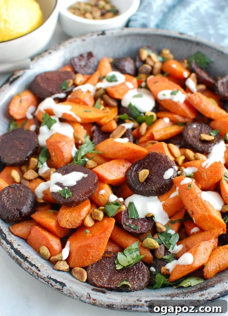Mediterranean Roasted Roots with Tahini Drizzle 2 Roasted Carrots and Beets with Tahini on metal plate, garnished with fresh herbs and pistachios.