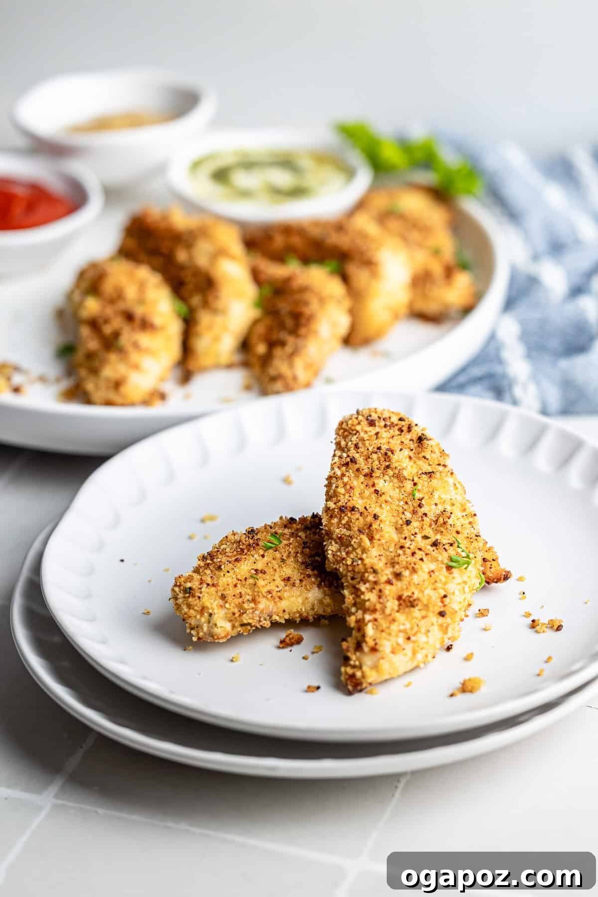 Golden Crispy Oven Baked Chicken Tenders 8 Baked chicken tenders plated on a white dish with herbs for garnish.