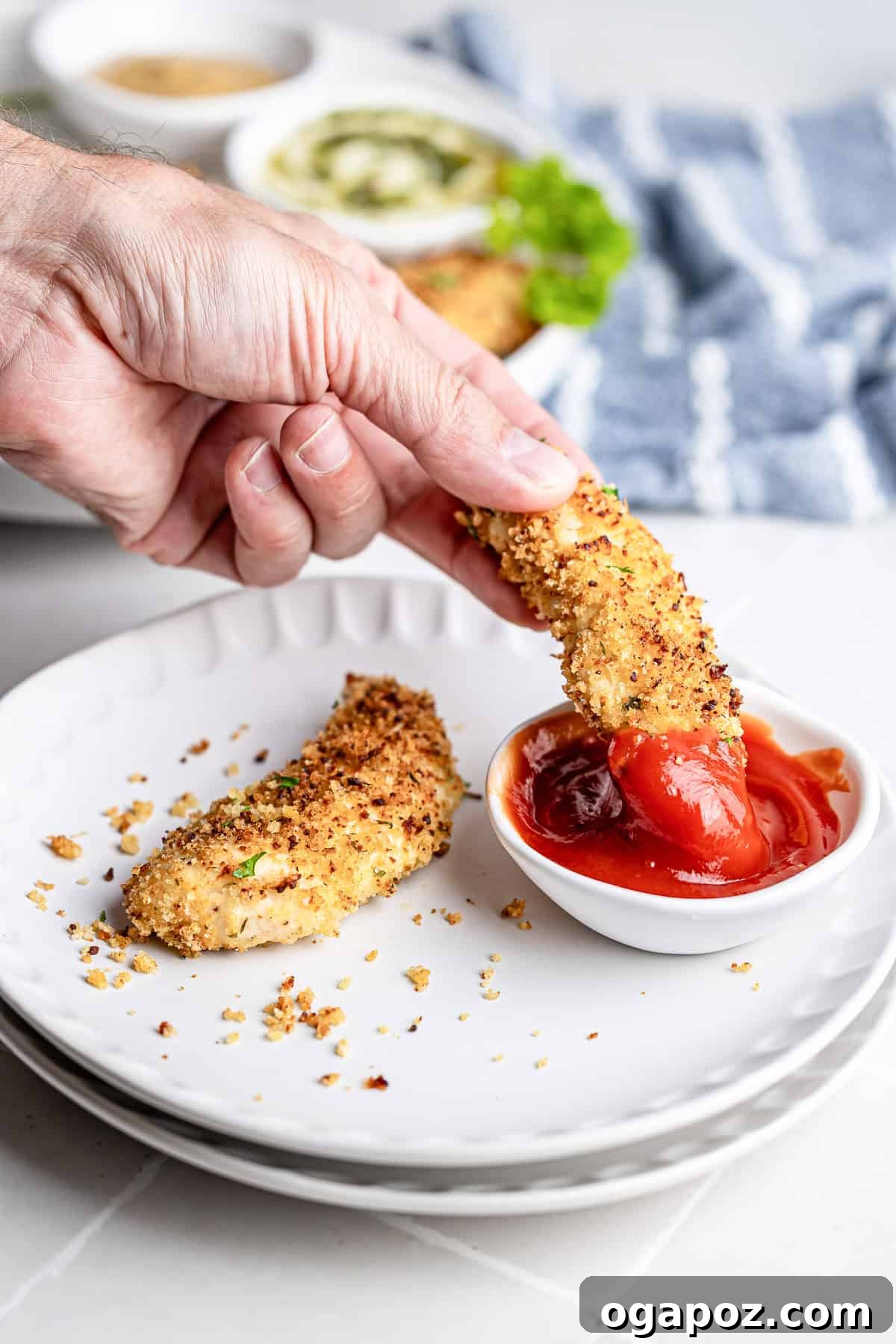 Golden Crispy Oven Baked Chicken Tenders 10 Baked chicken tender being dipped into a small bowl of ketchup.