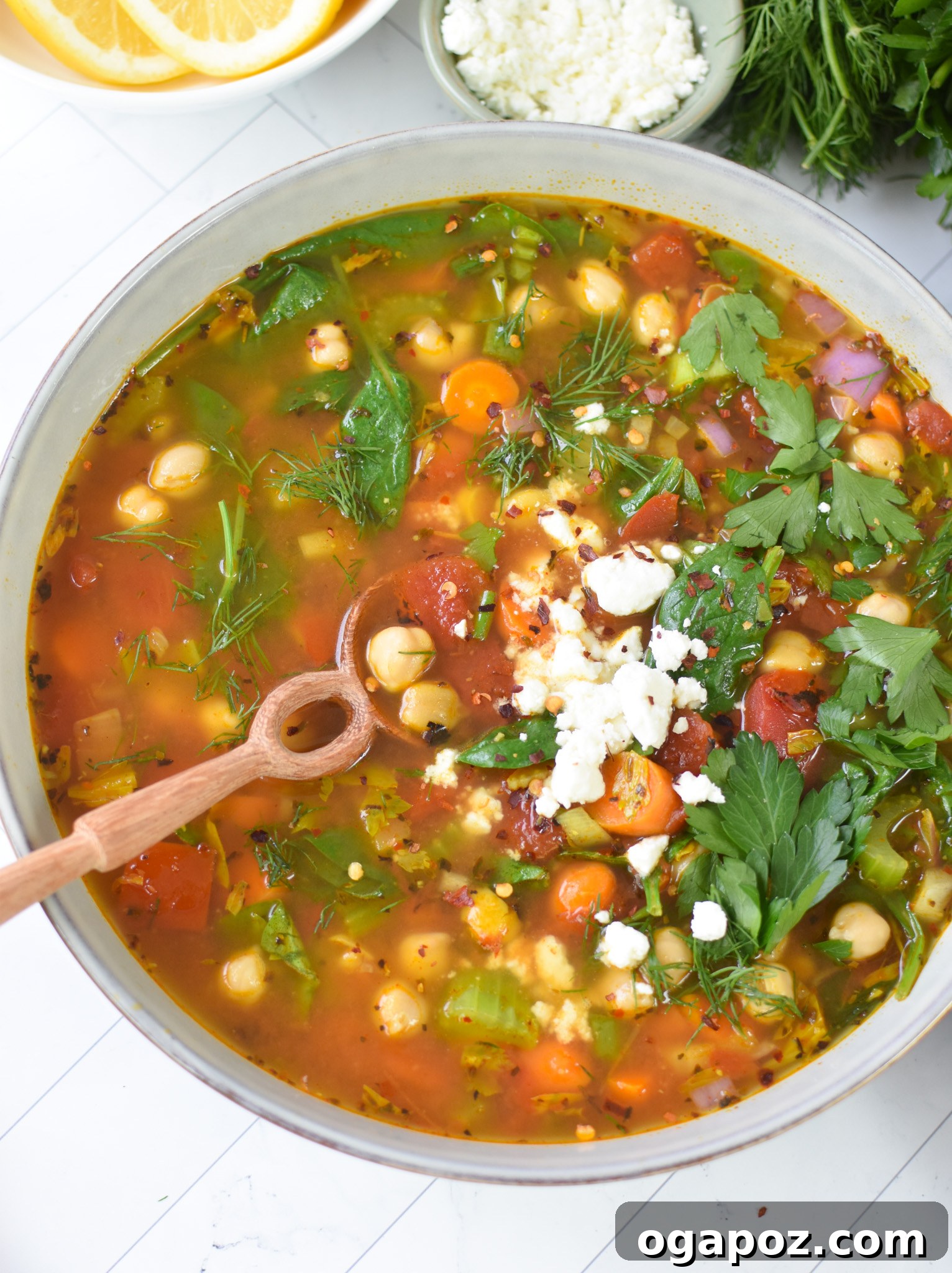 One-Pot Chickpea Comfort 3 Hearty Garbanzo Bean Soup served in a white bowl with a spoon, garnished with fresh feta cheese.