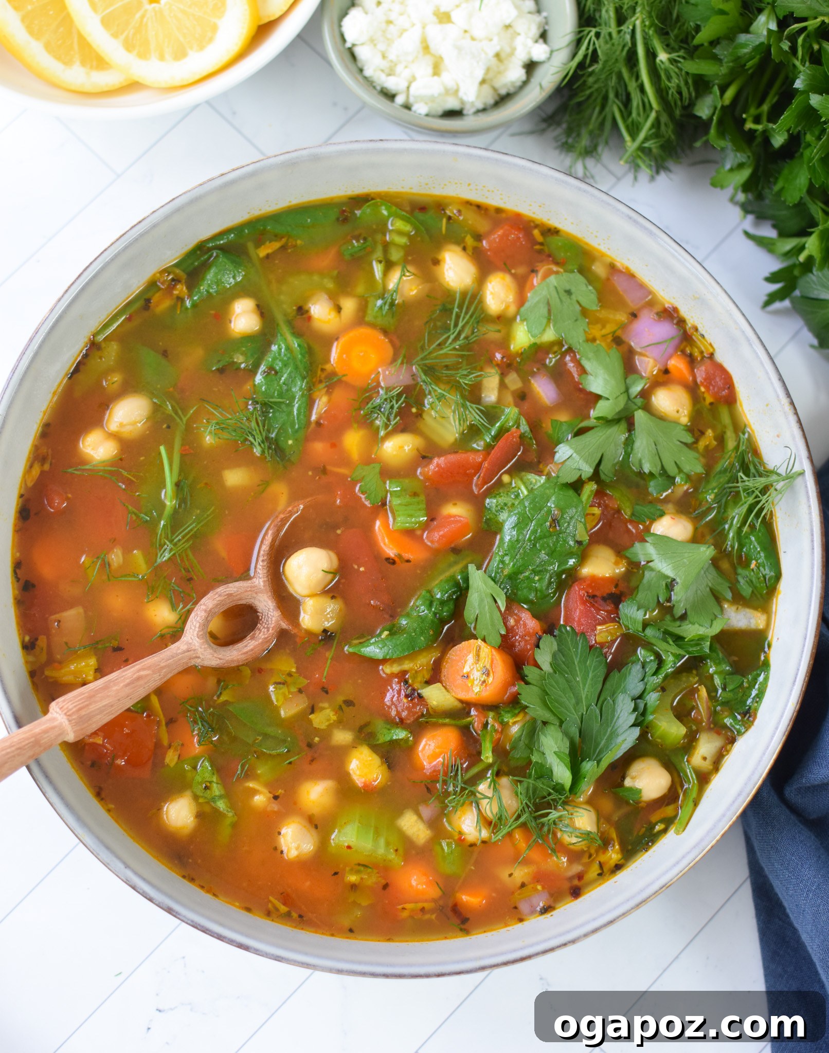 One-Pot Chickpea Comfort 6 A serving of Garbanzo Bean Soup in a blue bowl with a wooden spoon, ready to be enjoyed.