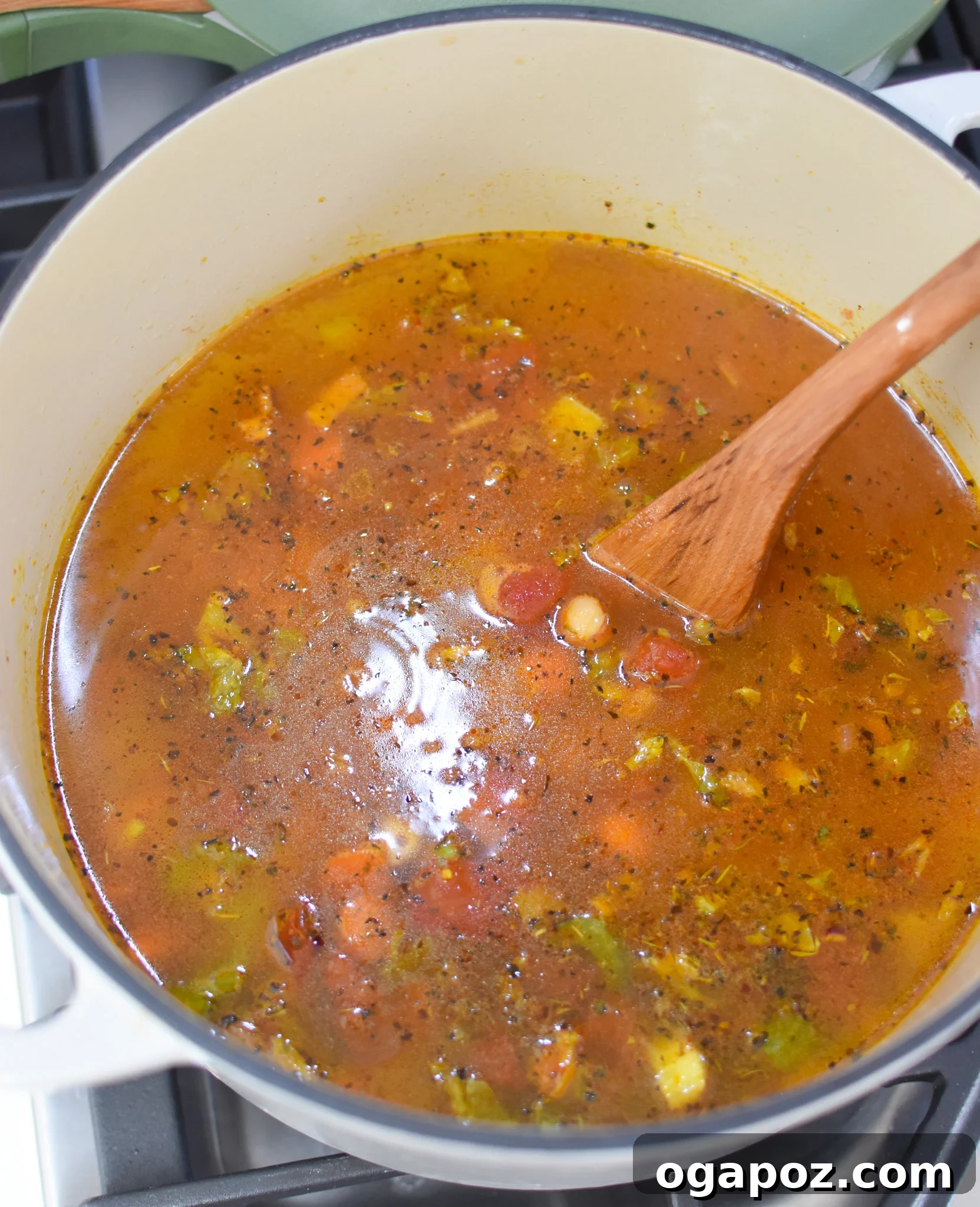 One-Pot Chickpea Comfort 8 Garbanzo Bean Soup simmering in a large pot with a spoon, showing the rich, vibrant broth and vegetables.