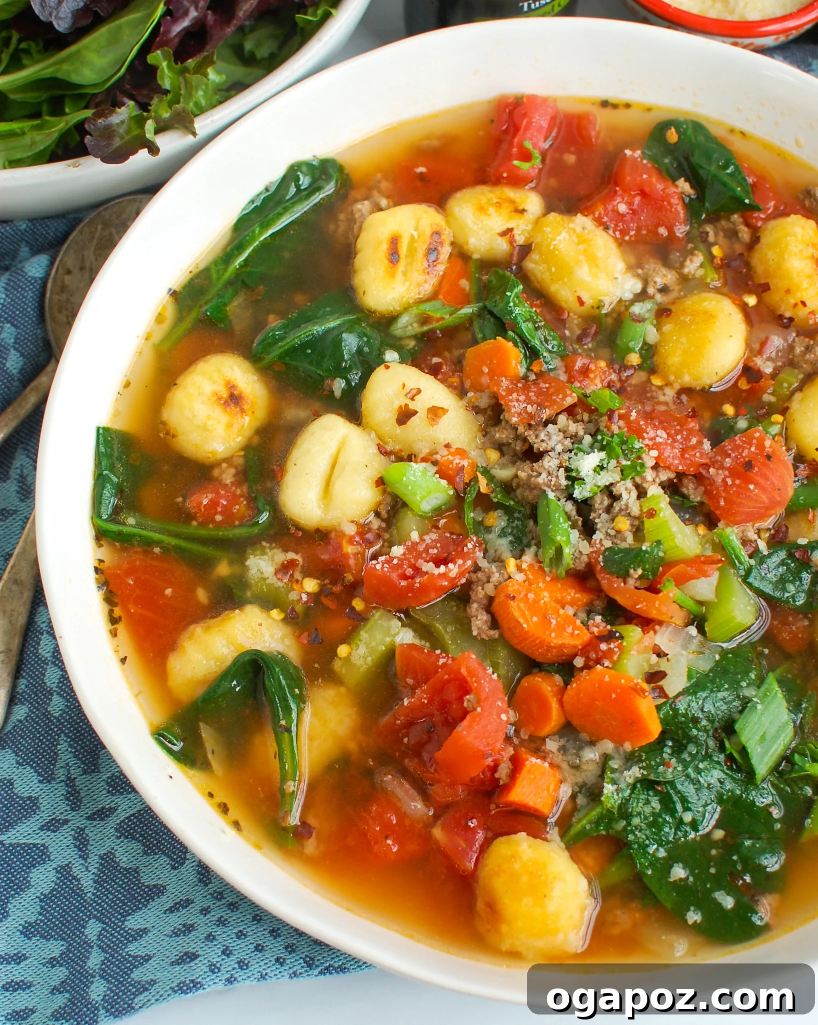Easy Sausage Gnocchi Soup with fresh spinach and herbs, served in a rustic bowl.