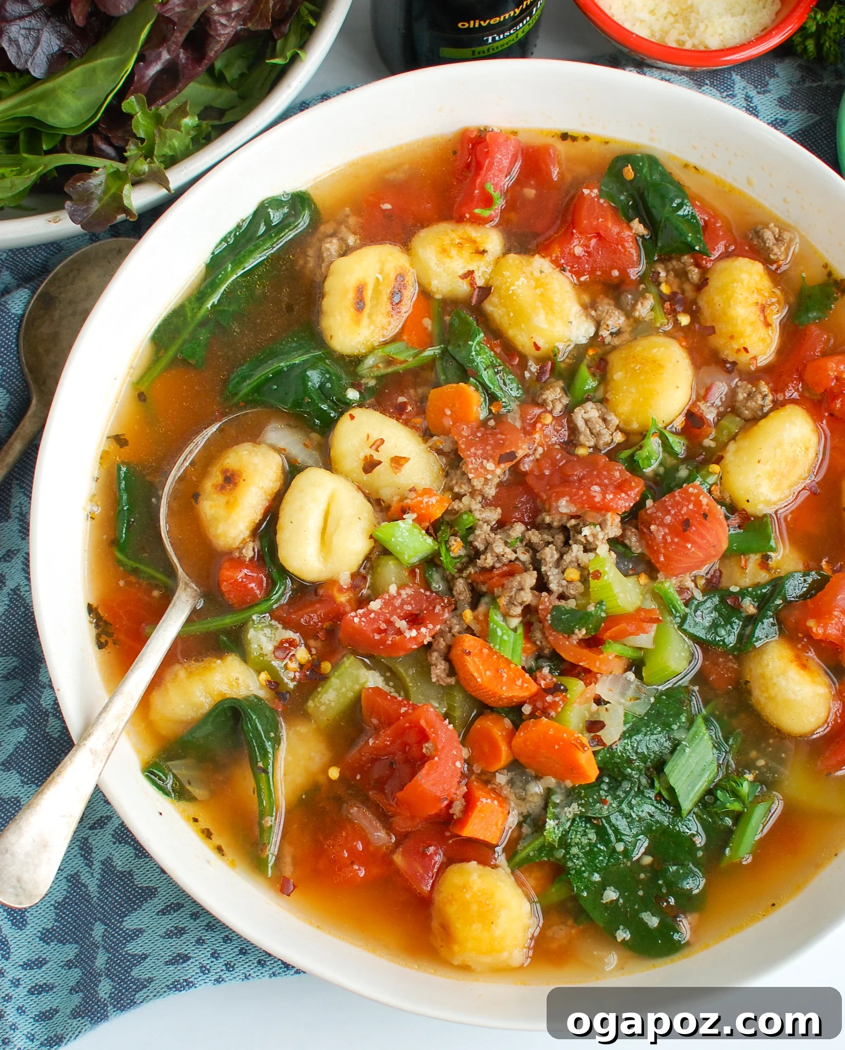 A close-up shot of a rustic bowl filled with Easy Sausage Gnocchi Soup, featuring a spoon dipped in it.