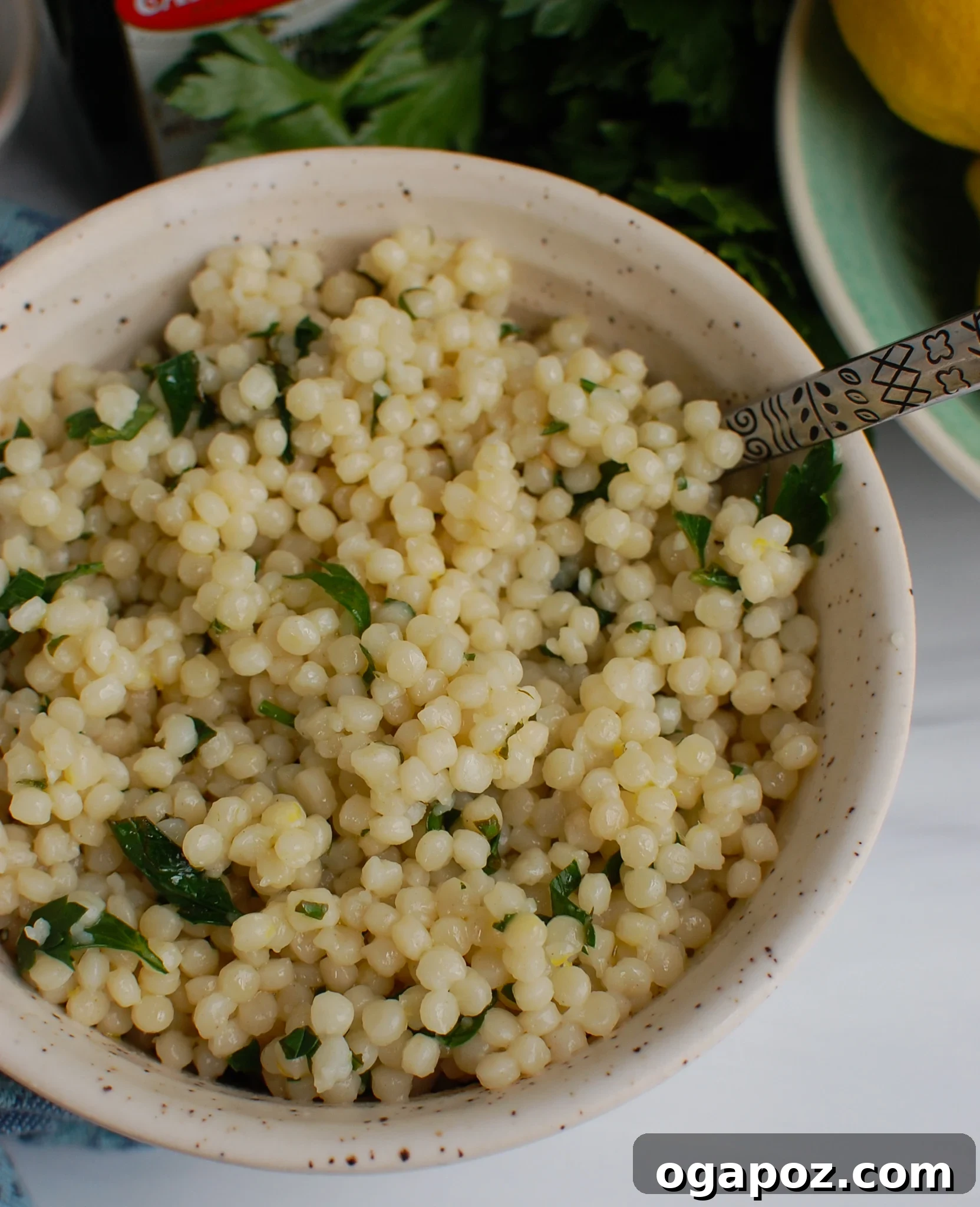 Sunshine Lemon Pearl Couscous 5 Fresh lemons and herbs arranged around a bowl of Lemon Pearl Couscous, highlighting its main ingredients.