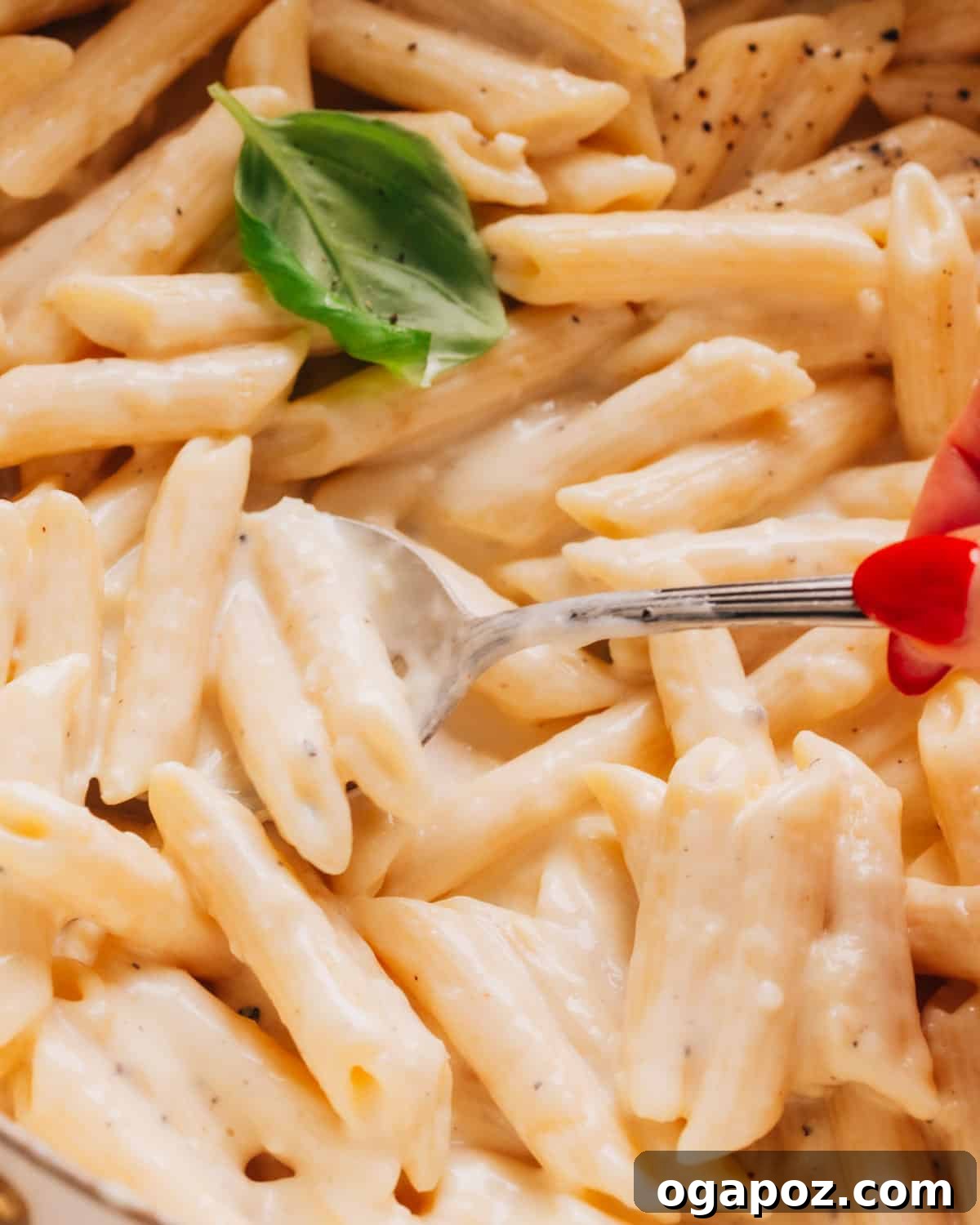 Easy Penne Alfredo: Your New Go-To Weeknight Meal 8 A close-up of creamy penne alfredo pasta in a bowl with a spoon, highlighting its smooth texture.