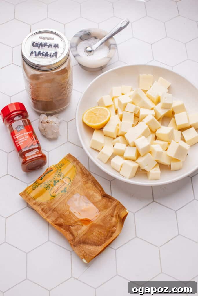 Creamy Butter Paneer 13 Various ingredients for marinating paneer, including spices, oil, and lemon, arranged on a rustic wooden board.