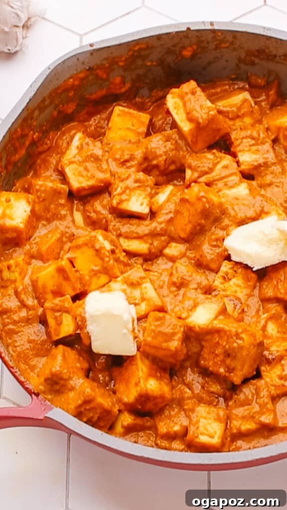 Creamy Butter Paneer 17 Adding a generous knob of butter to the simmering Butter Paneer Masala for an extra layer of richness and a glossy finish.