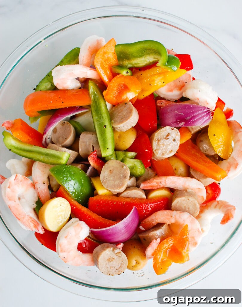 Effortless Sausage and Shrimp Foil Meals 5 Sausage and Shrimp Foil Packets ingredients in a clear bowl before cooking.