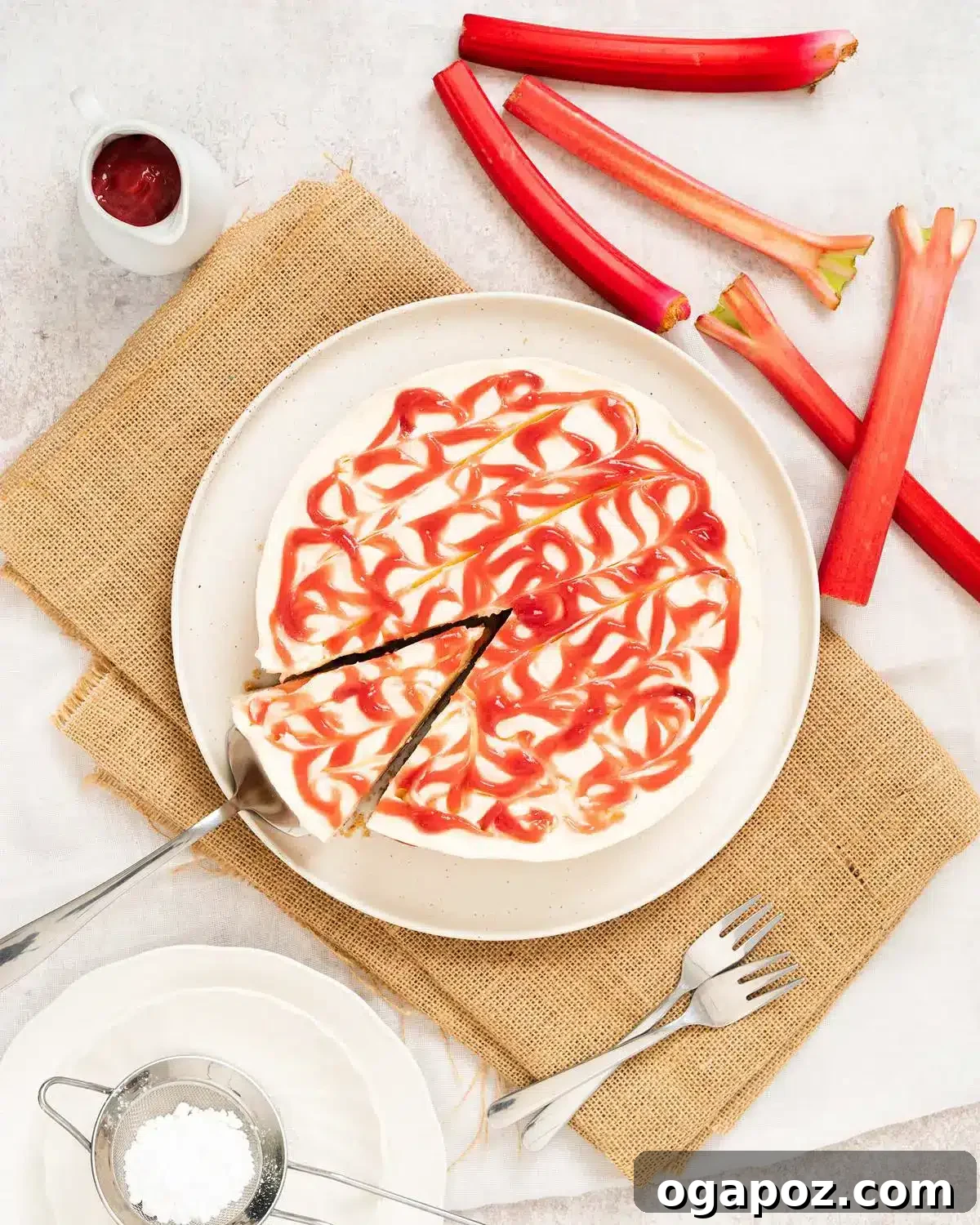 Our Go-To Easy Rhubarb Recipes 16 A slice of no-bake rhubarb cheesecake with a creamy pink filling and a crumbly biscuit base, garnished with fresh rhubarb curls.