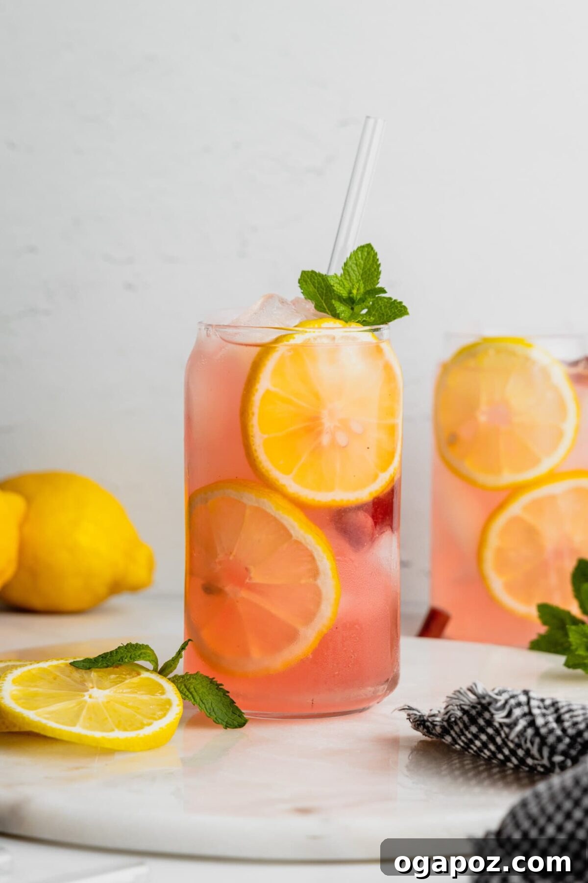 Our Go-To Easy Rhubarb Recipes 22 Glasses of vibrant pink rhubarb lemonade with lemon slices and rhubarb stalks as garnish, served over ice.