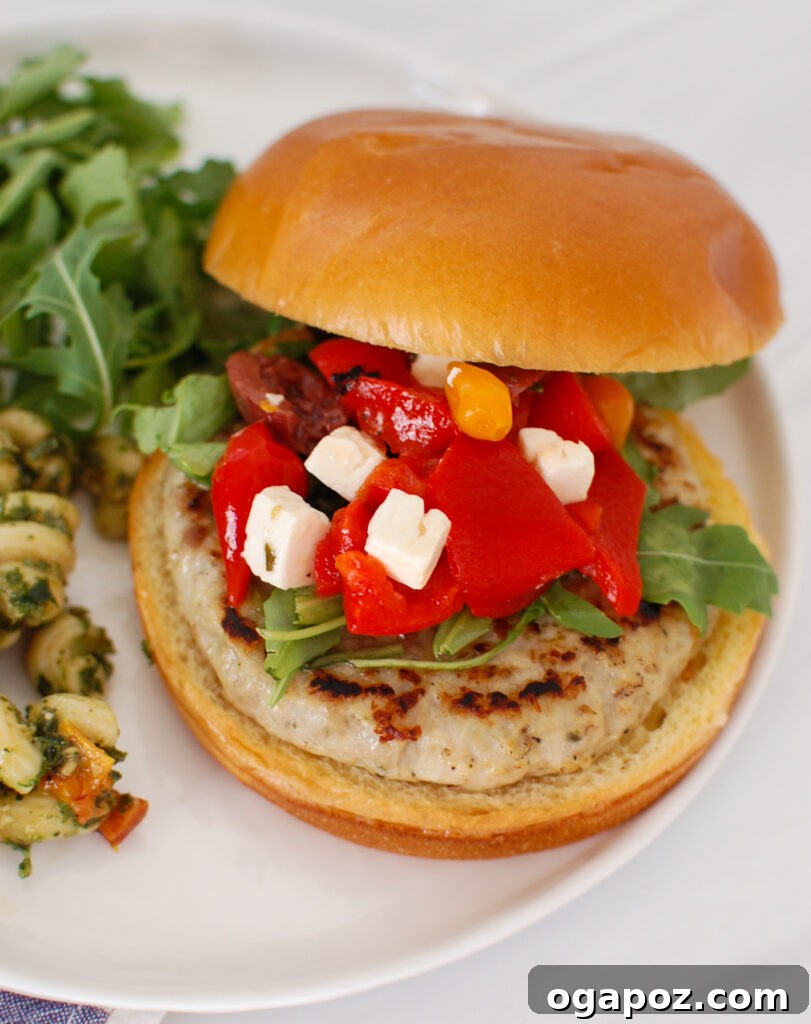 Zesty Greek Chicken Burgers 2 Delicious Greek Chicken Burgers on a white plate with fresh toppings