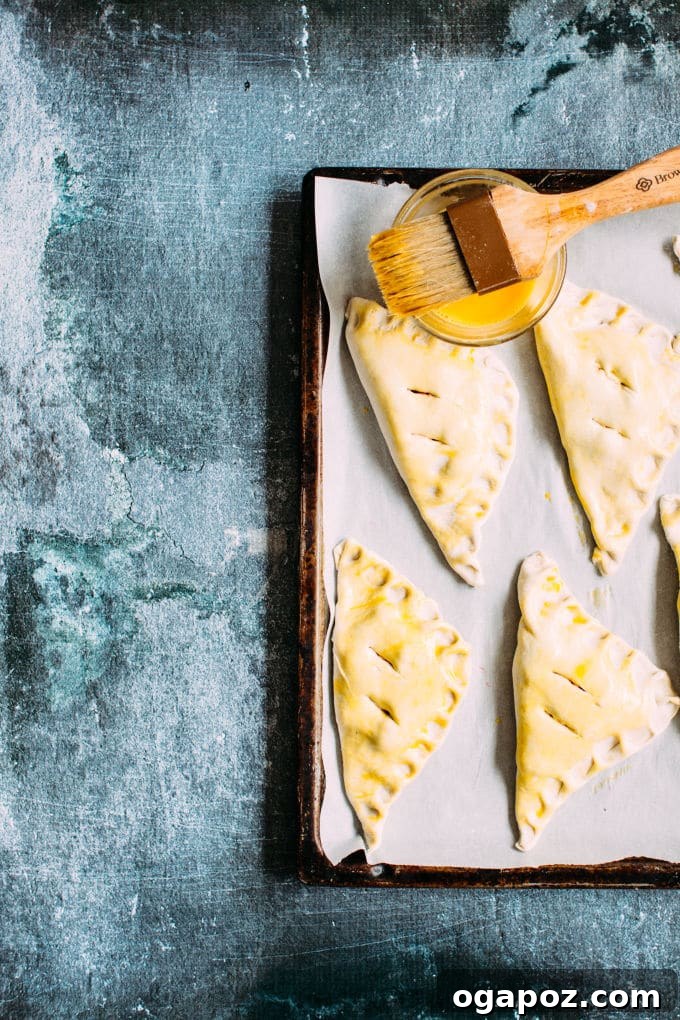 Almond-Kissed Cherry Cheese Turnovers 4 Cherry Cheese Turnovers being assembled on a wooden board: puff pastry filled with cheese and cherry pie filling, ready to be folded