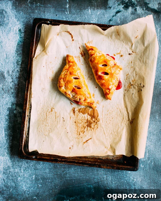 Almond-Kissed Cherry Cheese Turnovers 5 Freshly baked Cherry Cheese Turnovers on a cooling rack, perfectly golden brown and drizzled with almond icing, ready to be picked up
