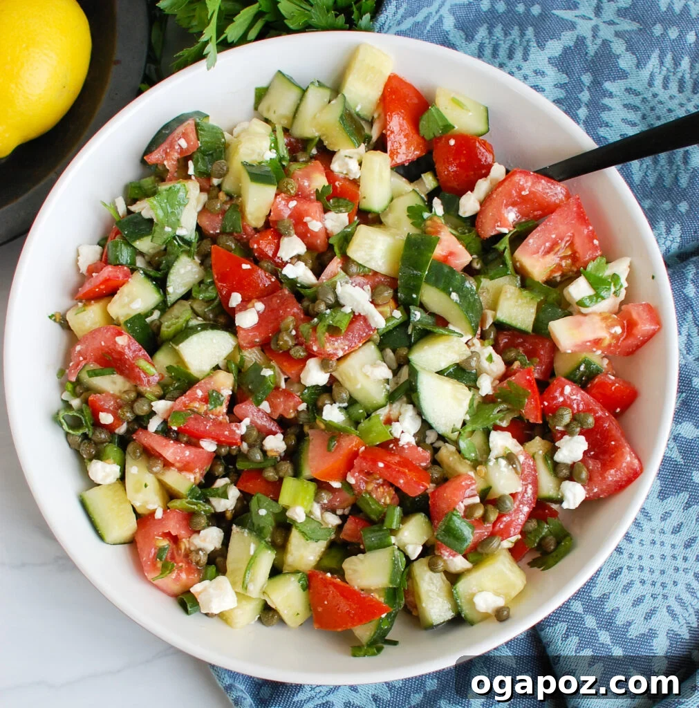 Close-up of fresh cucumber and capers in a white bowl, ready to be mixed into the salad.