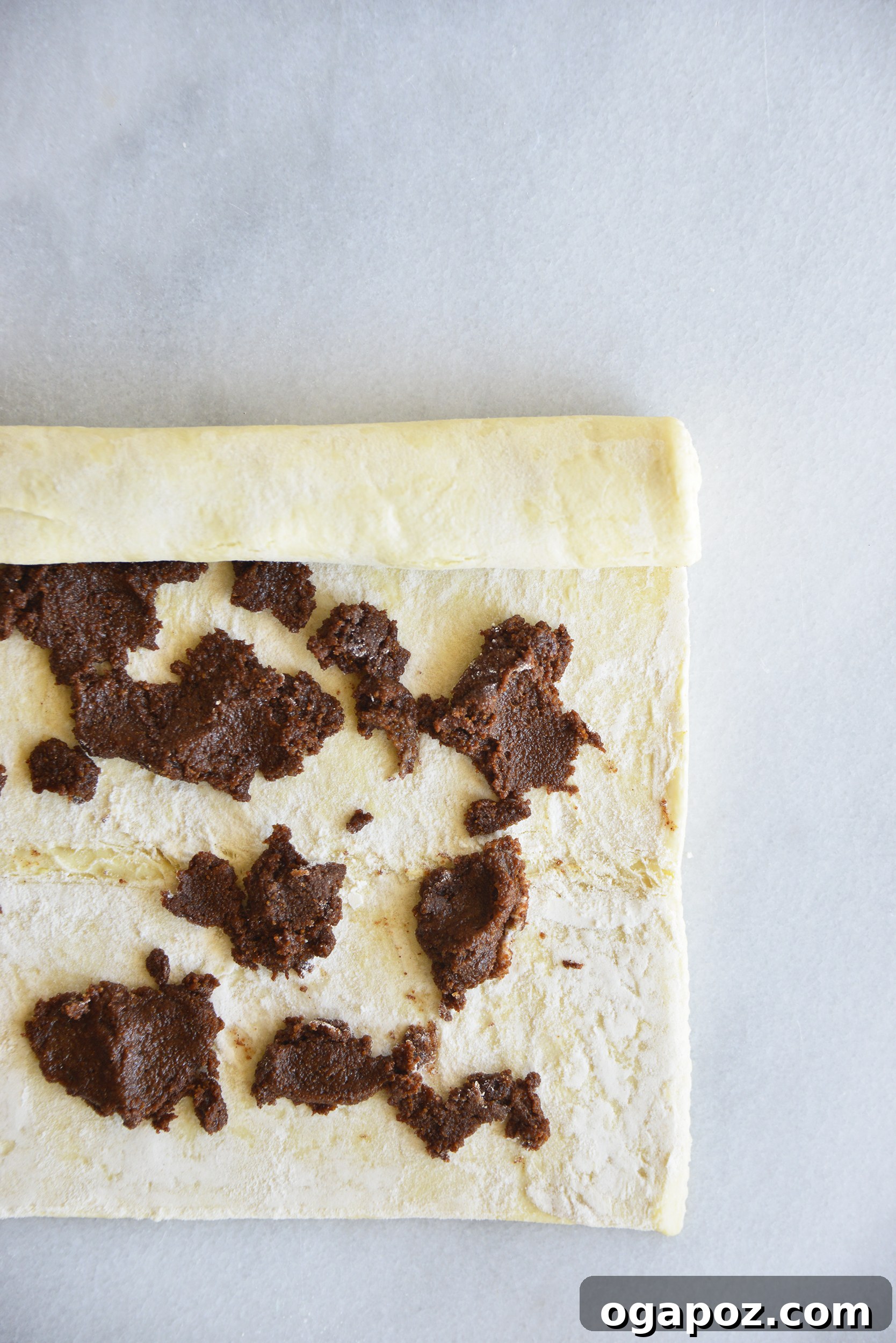 Effortless Cinnamon Puff Pastry Swirls 6 Puff pastry dough laid out flat with the cinnamon-sugar filling generously spread across its surface, prepared for rolling.