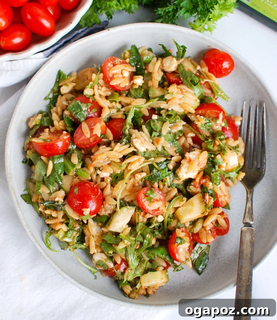 Vibrant Tomato Feta Orzo Salad 6 A serving of Tomato Feta Orzo Salad with a fork, emphasizing its delightful texture and freshness.